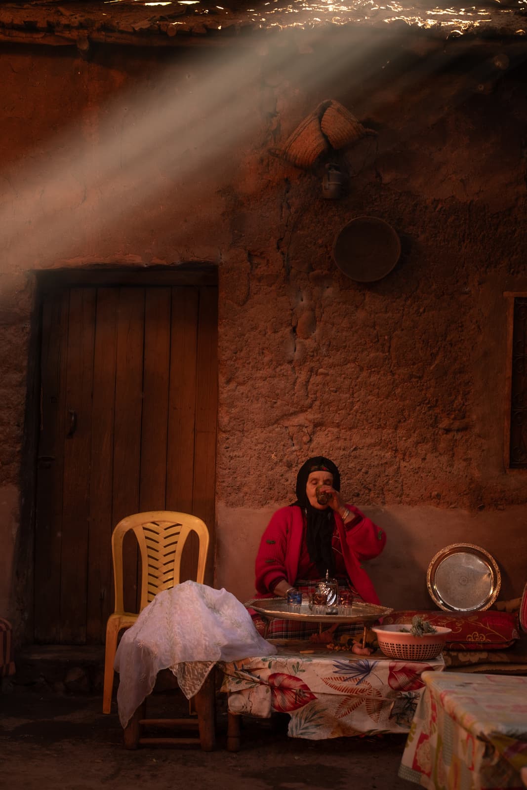 Woman sipping tea as golden light beams stream through rustic interior